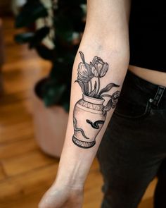 a woman's arm with a flower pot tattoo on it