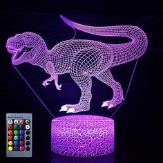 an illuminated dinosaur lamp with remote control and color changing lights on the table next to it