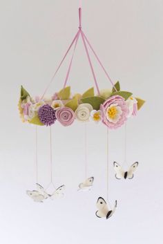 a mobile with flowers and butterflies hanging from it's sides in front of a white background