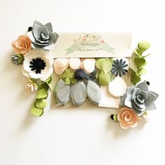 an assortment of felt flowers and leaves in a package on a white surface with a label