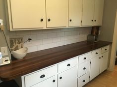 a kitchen with white cabinets and wooden counter tops