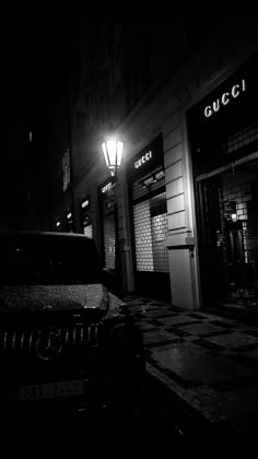 a black and white photo of a car parked in front of a gucci store