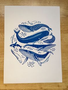 a blue and white drawing of whales in a circle on top of a wooden table