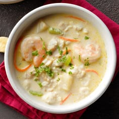 a bowl of soup with shrimp, carrots and celery on a red napkin