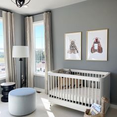 a baby's room with gray walls and pictures on the wall, including a white crib