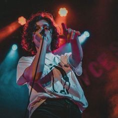 a man holding a microphone up to his mouth while standing in front of some lights