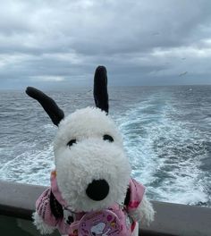 a stuffed animal is sitting on the edge of a boat looking out at the water