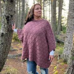 a woman standing in the woods wearing a pink sweater