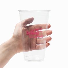 a hand holding a plastic cup with pink lettering on it