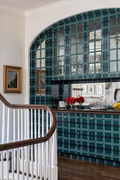 a kitchen with blue and green tiles on the wall, wood flooring and white railings