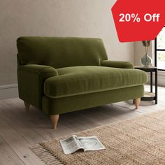 a green couch sitting on top of a wooden floor next to a table and window