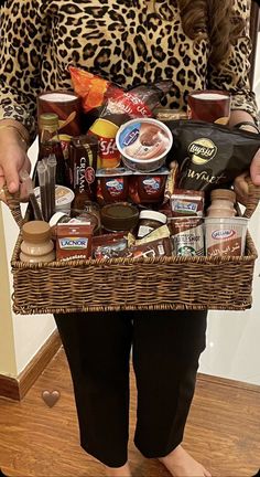 a woman holding a wicker basket filled with food and condiments in her hands