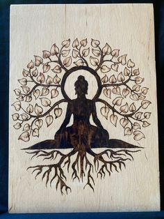 a wooden plaque with a woman sitting in the middle of a tree and roots on it