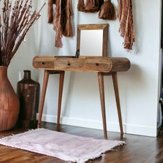 a wooden table with a mirror and some tassels on the wall behind it