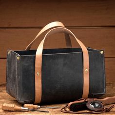 a black and brown leather bag sitting on top of a wooden table next to a pair of scissors