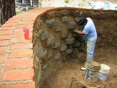 a man is working on some kind of wall made out of bricks and clay pots