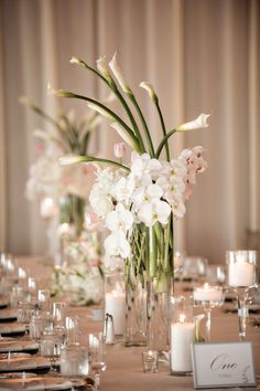 there is a vase with flowers and candles on the table in front of other place settings