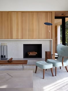 a living room with two chairs and a fireplace in the center, surrounded by wood paneling