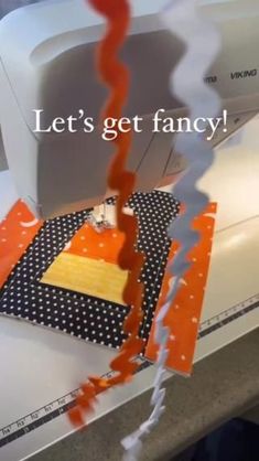 an orange and white sewing machine with the words let's get fancy on it