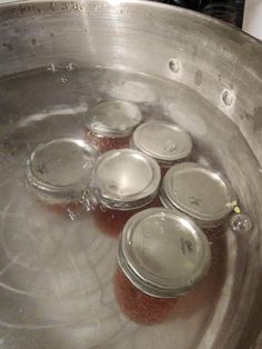 some jars are in the water on top of a stove burner and there is no lid