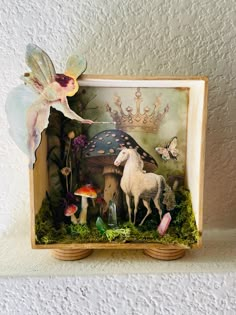 a miniature fairy scene with a unicorn, mushroom, and mushrooms in a wooden frame