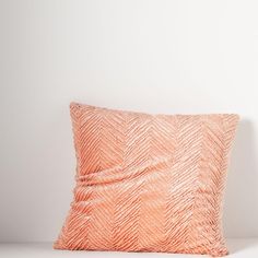 an orange pillow sitting on top of a white table