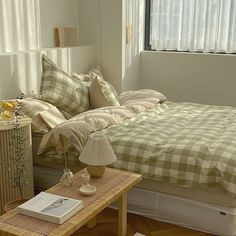 a bed sitting in a bedroom next to a table with a lamp on top of it