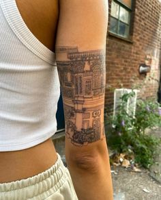 a woman with a tattoo on her arm is standing in front of a brick building