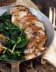 a pan filled with meat and greens on top of a table