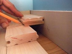 a person is using a pencil to cut wood planks with a pair of scissors