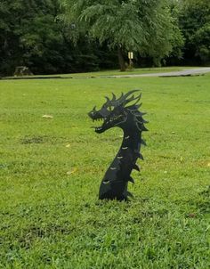 a black dragon statue sitting in the grass