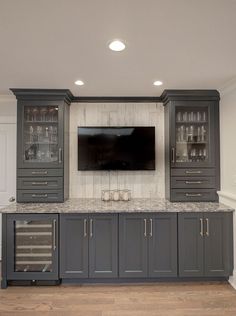 a large entertainment center with wine glasses on the shelves and a flat screen tv mounted above it