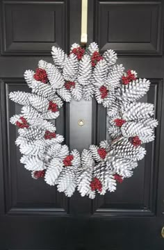 a wreath made out of pine cones and red berries is hanging on the front door