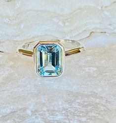 This classic bezel setting contains a beautiful 2.00ct natural sky blue topaz. The emerald cut stone measures approximately 8x6mm and the band is 2mm wide. The ring is available in sterling silver, and 14k white, yellow, or rose gold. Please send me a message if you need a size not listed. * This ring can be customized with any color center stone and can be made with a satin or a high polish finish. All items are handmade by me in my shop in Manalapan, NJ. Please message me with any questions. S Blue Emerald Cut Ring With Bezel Setting, Blue Emerald Cut Rings With Bezel Setting, Blue Topaz Ring With Emerald Cut And Bezel Setting, Emerald Cut Blue Topaz Jewelry With Bezel Setting, Blue Topaz Emerald Cut Jewelry With Bezel Setting, Classic Blue Topaz Ring With Rectangular Stone, Emerald Cut Faceted Topaz Ring In Fine Jewelry Style, Blue Topaz Emerald Cut Ring With Bezel Setting, Emerald Cut Blue Topaz Ring With Bezel Setting