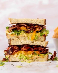 three sandwiches stacked on top of each other with bacon and lettuce in the middle