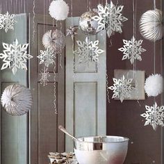 snowflakes are hanging from the ceiling in front of a bowl and other decorations