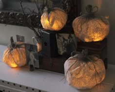 three decorative pumpkins sitting on top of a shelf next to a mirror with lights