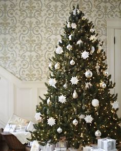 a decorated christmas tree with white and silver presents on the floor in front of it