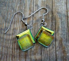 green and gold square earrings on wooden table with silver earwires hanging from hooks