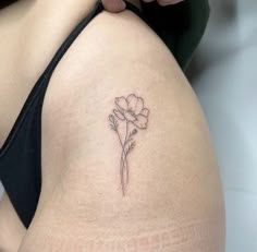 a small flower tattoo on the back of a woman's thigh