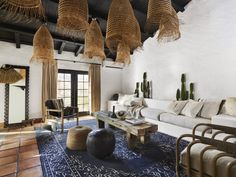 a living room filled with furniture and lots of hanging baskets on the ceiling above it