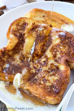 french toast with syrup being drizzled over it on a white plate,