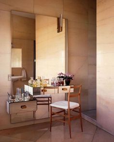 a chair sitting in front of a mirror next to a vanity