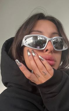 a woman wearing sunglasses and holding her hands to her face