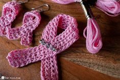 pink crocheted scarf and matching earrings on wooden table with knitting needles in background