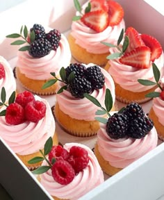 a box filled with cupcakes covered in frosting and topped with fresh berries