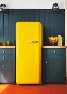 a yellow refrigerator sitting in the middle of a kitchen next to some drawers and cabinets