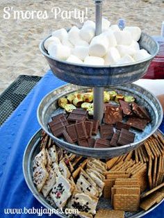 there is a platter with marshmallows and crackers on the beach