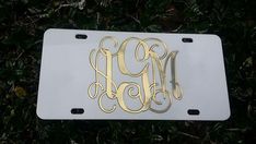 a white license plate with gold monogrammed letters