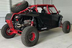 a black and red buggy parked in front of a garage door with two large tires